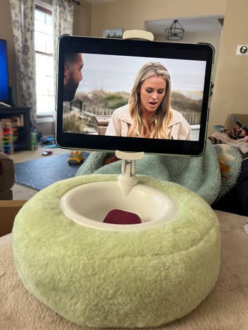 Tablet holder with a cozy, circular cushion base, displaying a video country with 2 radical talking indoors