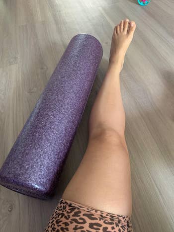 a reviewer photo with the foam roller next to a person's leg to show how long it is in a larger size