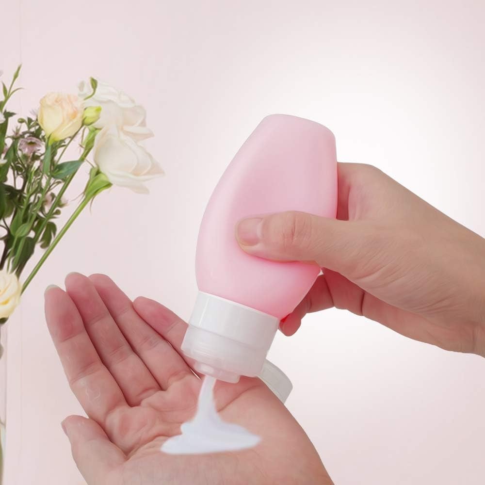 Hand squeezing lotion from a pink bottle into palm, flowers in background; suitable for moisturizing skin care