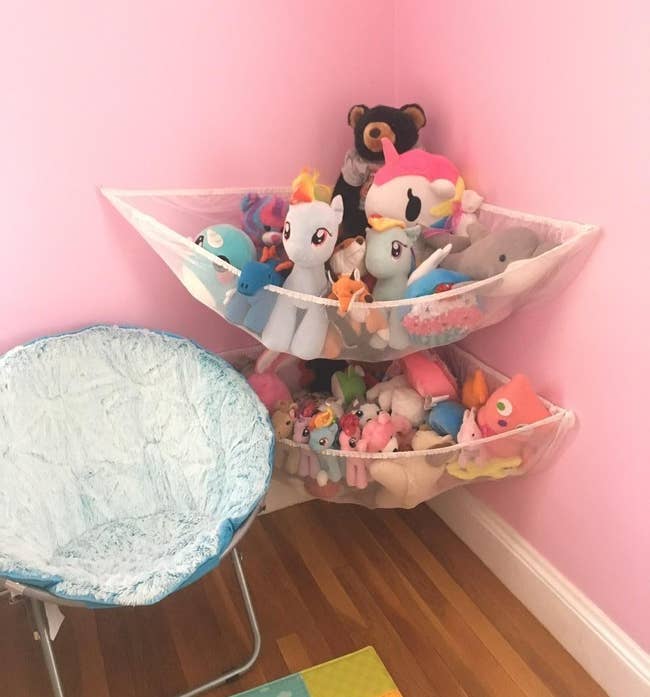Reviewer's photo showing a pair of white hammocks hanging on a pink wall and holding stuffed animals 