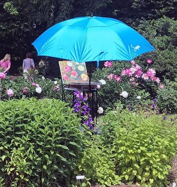 reviewer photo of the blue umbrella set up in a garden over an easel 