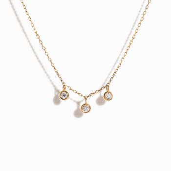 a gold necklace with three bezel-set diamonds