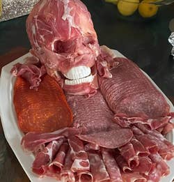 the skull covered with prosciutto on a platter of meat