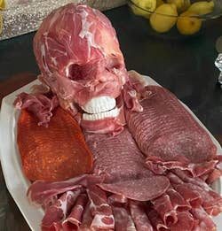 the skull covered with prosciutto on a platter of meat