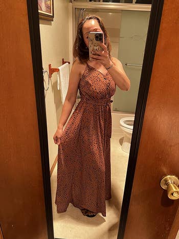 Reviewer in mirror taking selfie, wearing a sleeveless patterned maxi dress with a belted waist
