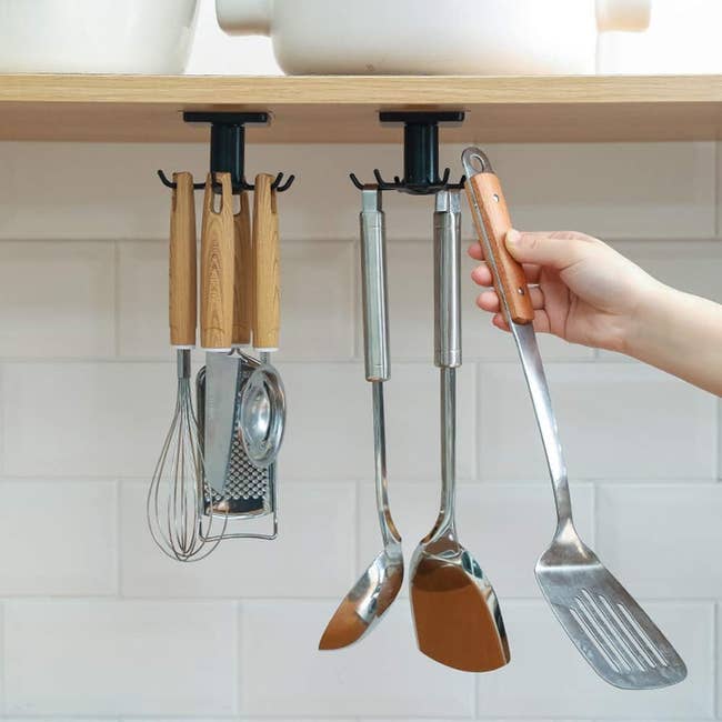 Hand selecting a kitchen utensil from a mounted holder under a shelf