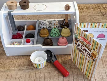 A toy ice cream counter playset with various pretend flavors and accessories
