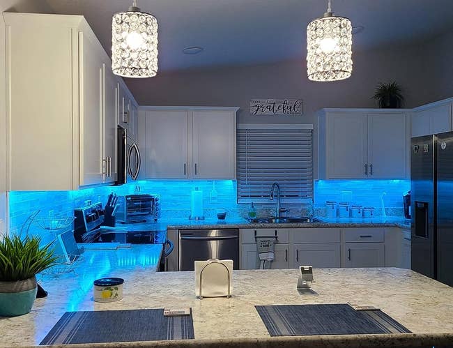a kitchen lit up with blue led lights under the cabinets