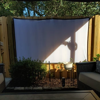 a reviewer photo of the included projection screen set up in a backyard 