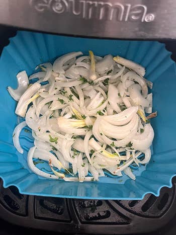 a reviewer's onions in a blue silicone blue air fryer basket liner