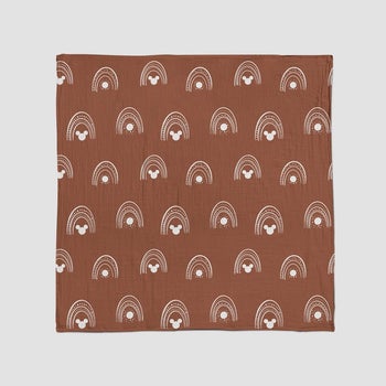 a burnt orange blanket with tiny rainbows and mickey on it in white