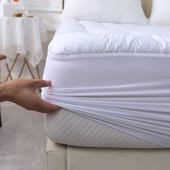hand lifting the mattress cover from underneath the mattress