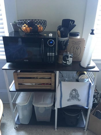 Reviewer image of black and white microwave cart with black microwave and kitchen supplies on each shelf