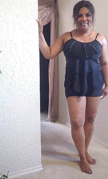 a reviewer wearing a black ruffle tankini top with matching black shorts 