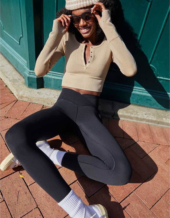 model wears black high-rise crossover leggings with a solid henley top