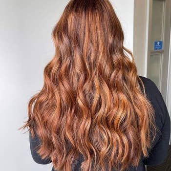Reviewer with long wavy red hair after using the spray