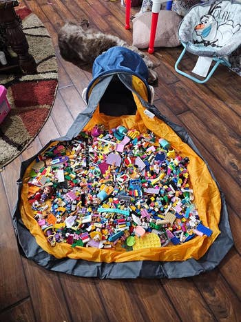 Bag connected  the floor, unfastened  to show  assorted  artifact  gathering  blocks, showcasing a retention  solution   for organizing children's play   items