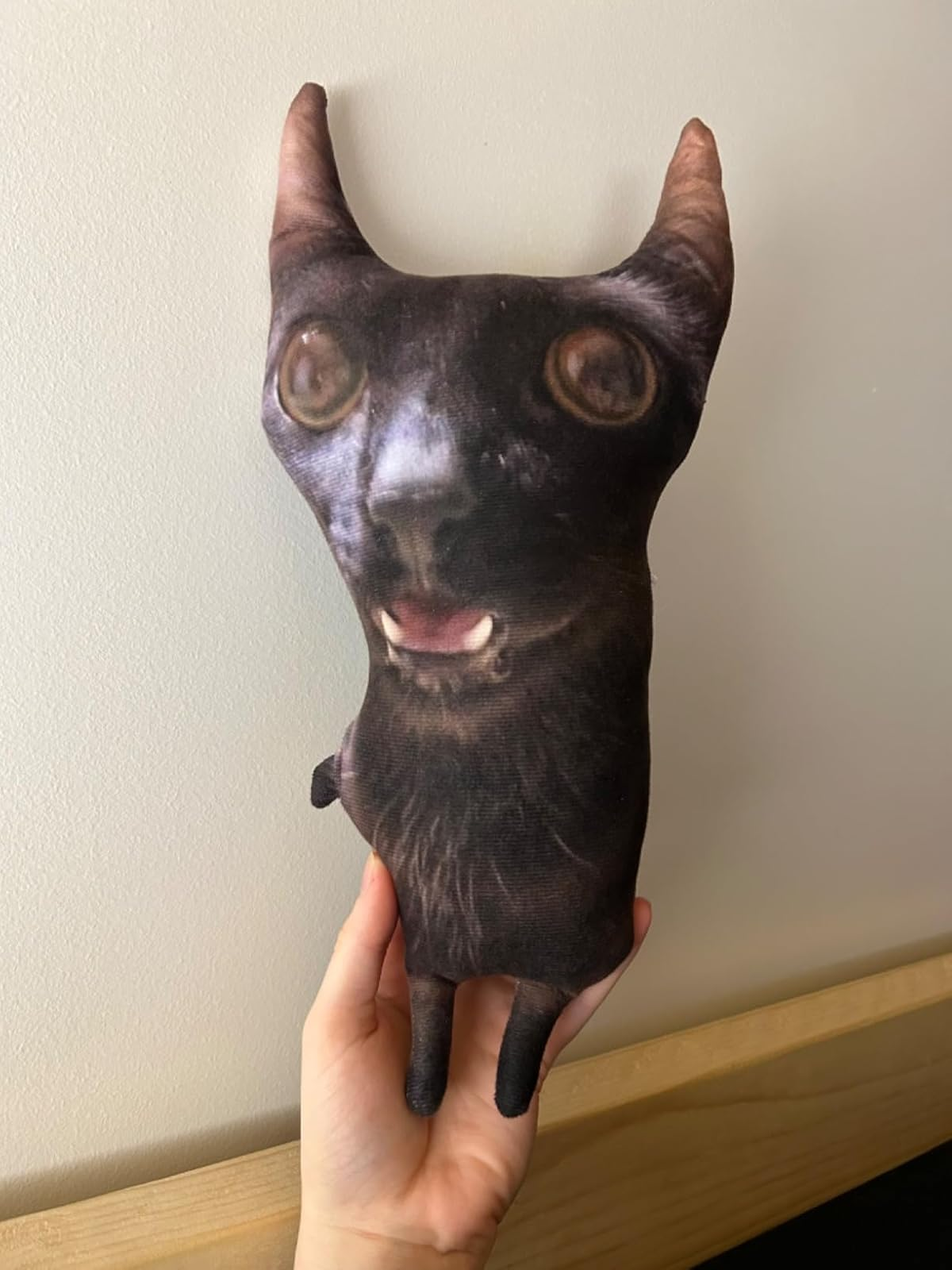 Plush toy shaped like a cat’s head with exaggerated eyes and ears