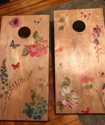 Two cornhole boards with floral and butterfly designs
