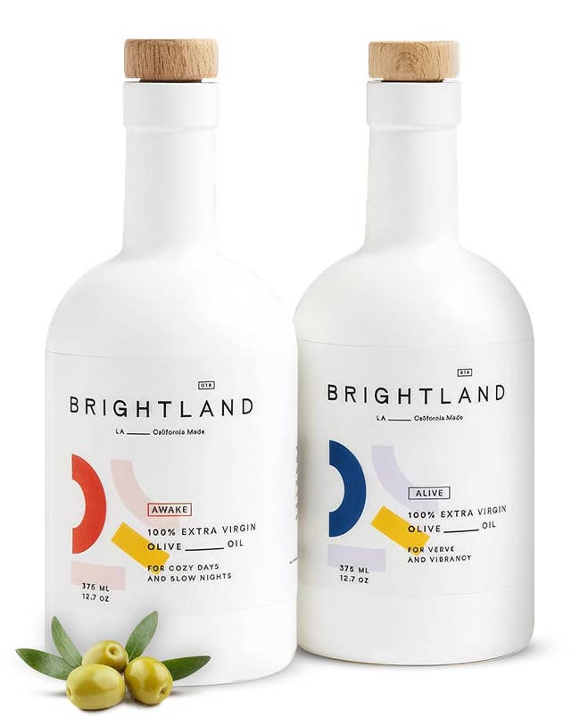 Two bottles of Brightland olive oil with wooden caps, labeled