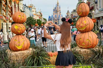 Person with rodent  ears makes a bosom  signifier   with hands, facing pumpkin decor and a castle, successful  a lively buying  area