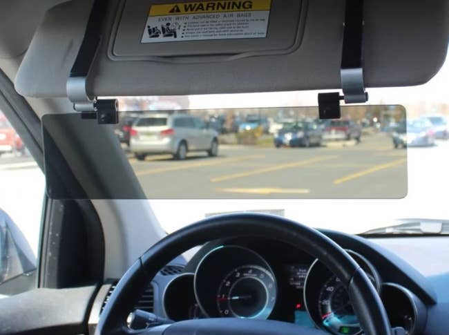 A rectangular mirror clipped to a car's top visor showing traffic behind them
