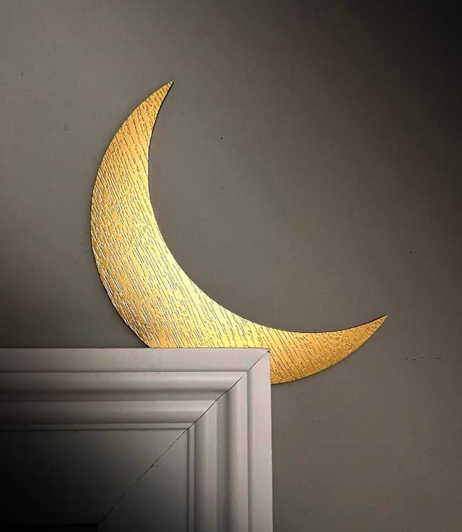 Gold crescent moon wall decor above a white cabinet