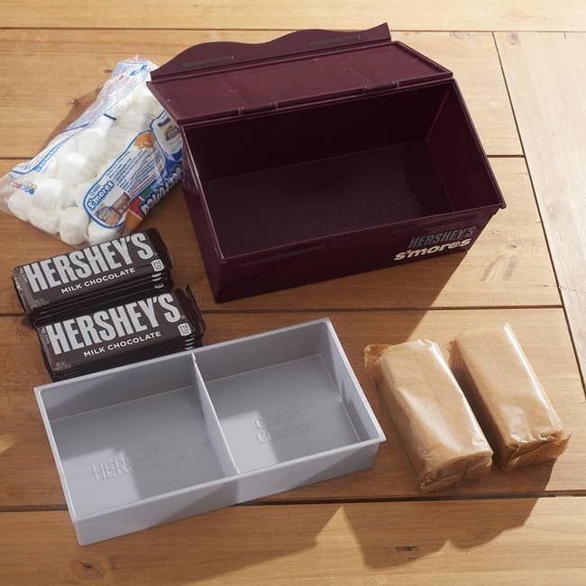 S'mores caddy with compartments for graham crackers, chocolate, and marshmallows on a wooden surface