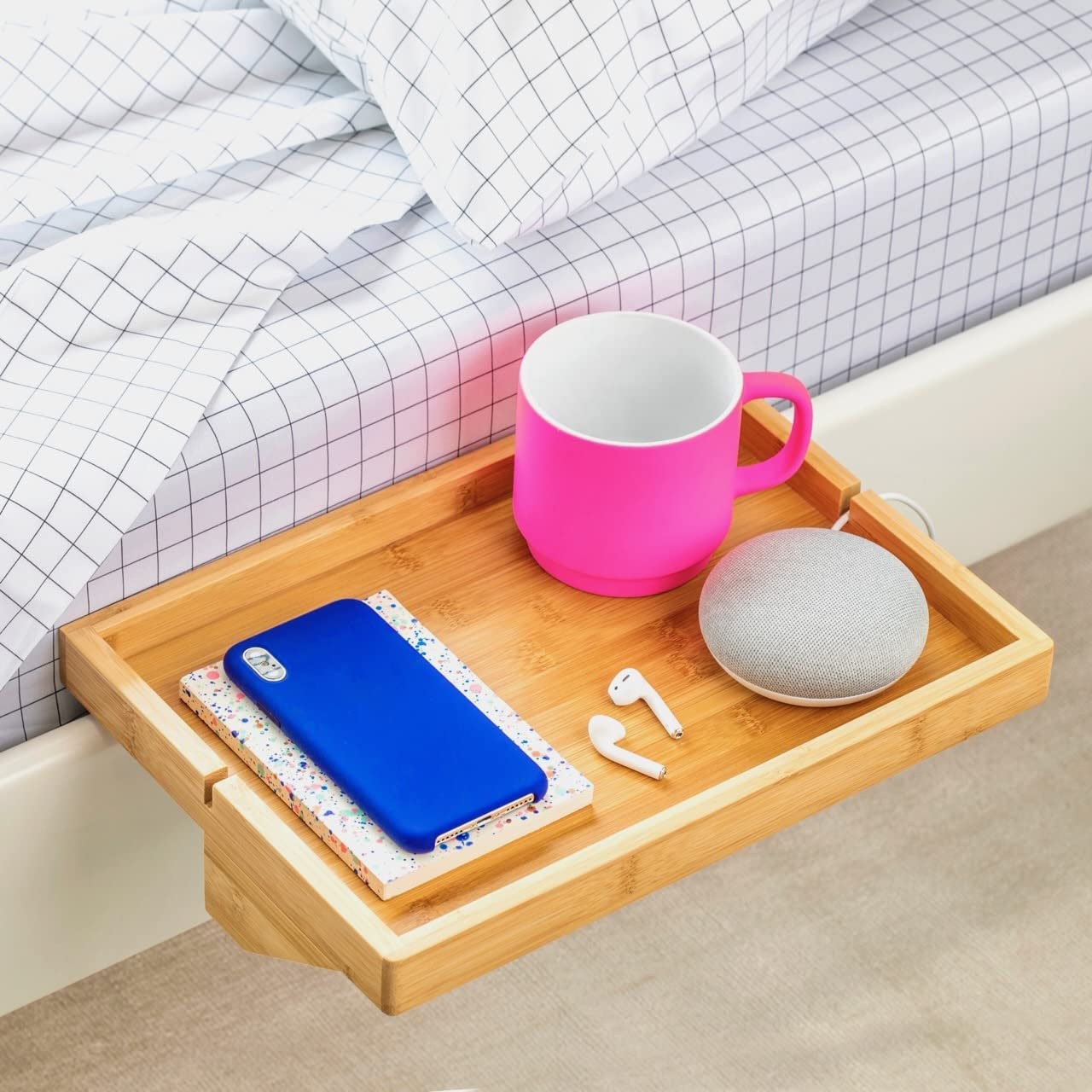 Light wood shelf attached to a bed frame holding accessories and a phone 