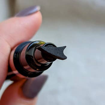 Close-up of a manus holding a achromatic constitution applicator with a unsocial sponge tip, suitable for precise application, perfect for a buying article