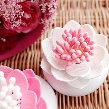 Close-up of a decorative flower ornament with pink and white petals, placed on a wicker surface, alongside another similar ornament in the background