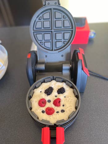 Waffle maker with uncooked batter and berries