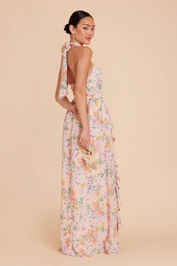 Woman in a floral maxi dress with ribbon details on the shoulder, posing for a shopping article