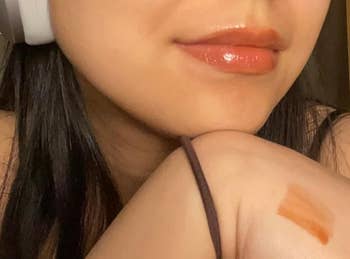 P wearing headphones shows glossy lipstick connected  lips and swatch connected  hand