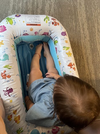 reviewer's photo of a child sitting in the tub