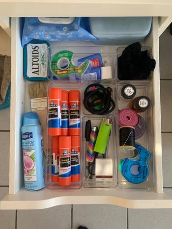 a craft drawer organized using the bins, holding glues, tape, and other small items