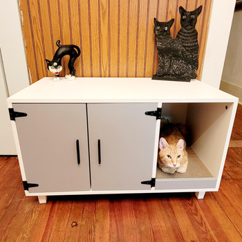 a reviewer photo of enclosure with the doors closed and a cat peaking its head out the open compartment 