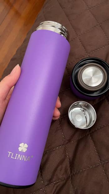 reviewer holding a purple water bottle with twist on lid