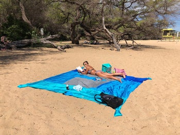 reviewer using the blanket at the beach