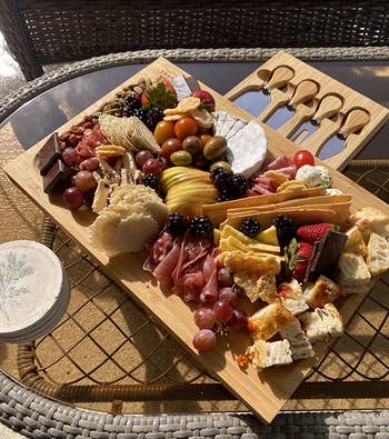 reviewer photo of the charcuterie board filled with cheese, meat, and fruit on a picnic table