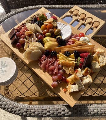 reviewer photo of the charcuterie board filled with cheese, meat, and fruit on a picnic table