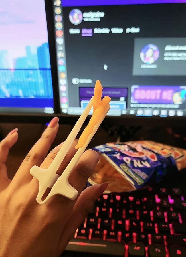 a reviewer using the chopsticks to eat snacks while using their computer