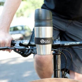 a model riding a bike with the cup holder attached to bike handles and aa tumbler cup inside 