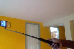 Person&rsquo;s hand holding a selfie stick with a smartphone attached
