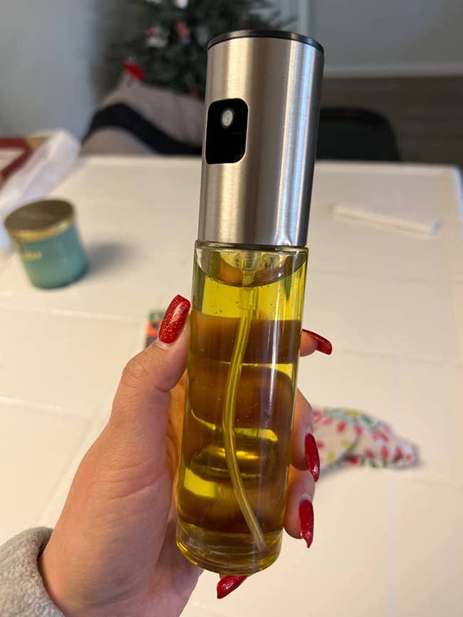 a reviewer holding the spray bottle filled with oil 