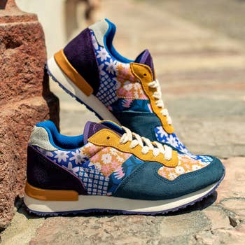 A pair of colorful, patterned sneakers displayed on a cobblestone street 