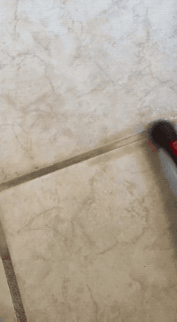 Close-up of a grout cleaning brushwood  scrubbing a tiled floor, demonstrating effectual  cleaning of grout lines for a buying  article