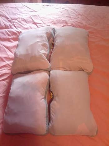 Four beige pillows arranged to signifier  a larger cushion connected  a pinkish  bedspread. Perfect for a location  décor feature