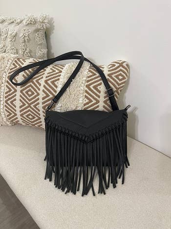 Fringe handbag with braided details on a patterned cushion. Stylish accessory for a chic look