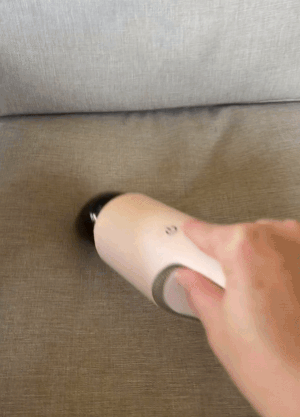 gif of reviewer vacuuming couch cushions with pink vacuum